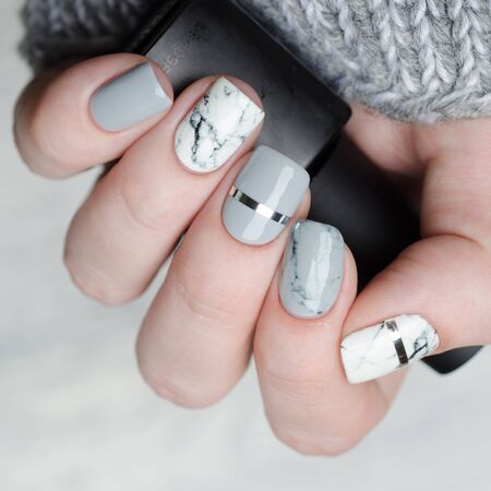 white and grey marble manicure with silver stripe on grey backgroundの写真素材