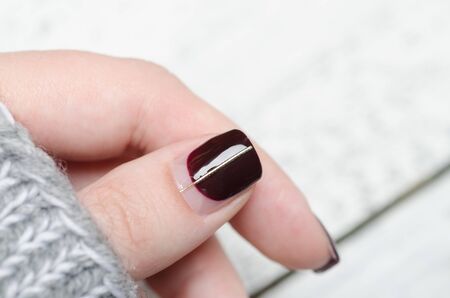Burgundy manicure with negative space and Golden line on grey fur backgroundの写真素材