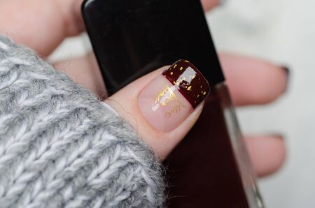 Bordeaux french manicure with gold flakes with gray sweaterの写真素材
