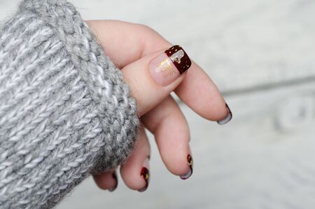 Bordeaux french manicure with gold flakes with gray sweaterの写真素材