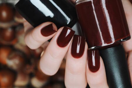 Burgundy brown manicure on a background of acorns