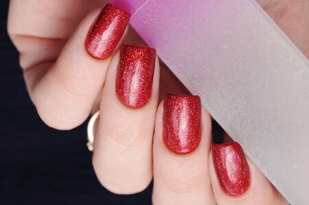 Hand holds nail file red manicure on white backgroundの写真素材