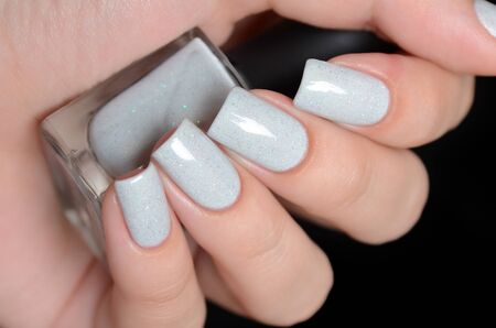 grey shimmer manicure on a black backgroundの写真素材