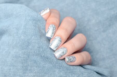 winter grey shimmer manicure with a ftosty pattern on a gray backgroundの写真素材