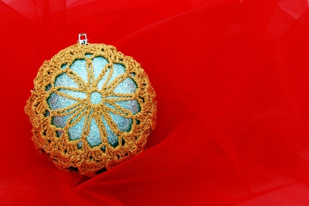 Homemade ornament with a snowflake design displayed on a red material background.の写真素材