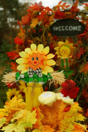Thanksgiving or festive autumn display with a scarecrow, cupcakes, and a welcome sign in the background の写真素材
