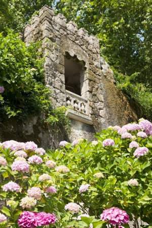 An ancient tower with a stone balcony surronded in beatuiful gardens.の写真素材