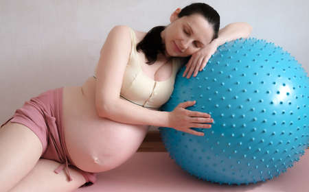 A pregnant woman goes in for sports with a fitness and yoga ball. Concept food, healthy lifestyle.の写真素材