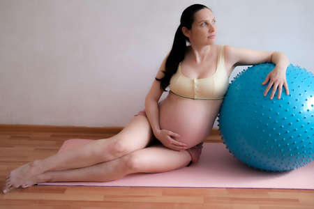 A pregnant woman goes in for sports with a fitness and yoga ball. Concept food, healthy lifestyle.の写真素材