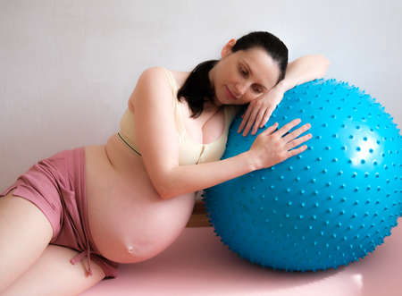 A pregnant woman goes in for sports with a fitness and yoga ball. Concept food, healthy lifestyle.の写真素材