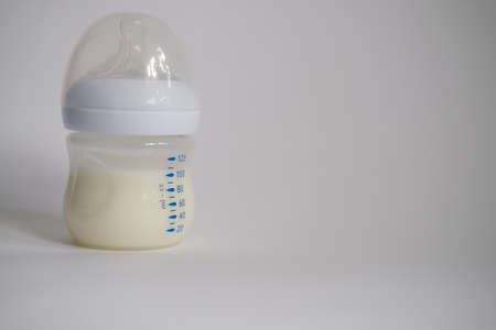 The electric breast pump is on the table in the kitchen. Breast pump with milk. Give expressed breast milk. Breast care for a young motherの写真素材