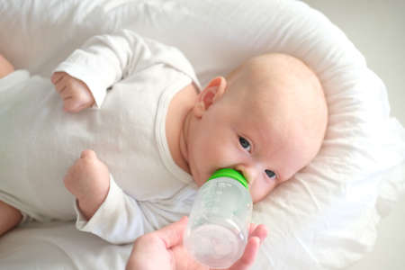 Close-up portrait of a child. A newborn baby drinks milk from a bottle
