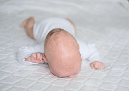 A newborn baby lies on a white blanket. Close-up portrait of a child