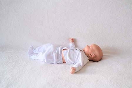 A newborn baby lies on a white blanket. Close-up portrait of a child.