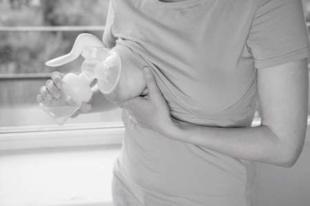 Young woman holding a machine for expressing breast milk. Concept breastfeeding. Breast pump close-upの写真素材