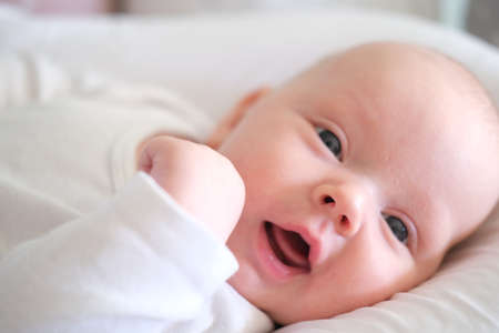 A newborn baby in white clothes lies on the bed. Portrait of a lying cute little childの写真素材