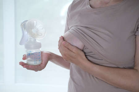 Young woman holding a machine for expressing breast milk. Concept breastfeeding. Breast pump close-upの写真素材