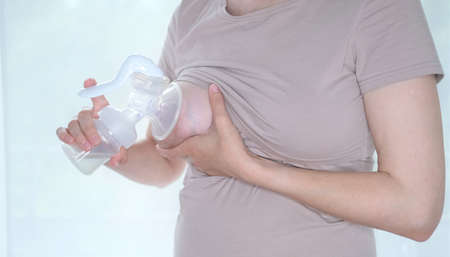 Young woman holding a machine for expressing breast milk. Concept breastfeeding. Breast pump close-upの写真素材
