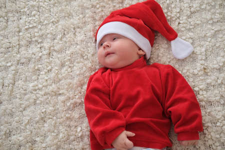 Santa claus baby lying on white blanket Christmas toddler in Santa hatの写真素材