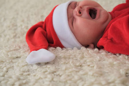 Santa claus baby lying on white blanket. Beautiful little baby celebrates Christmas.の写真素材