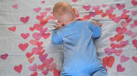 Newborn baby - boy or girl lies on a white background with red and bright pink hearts.