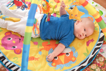 Newborn baby playing Portrait of a cute 3 month old baby lying on a bright blanket.の写真素材
