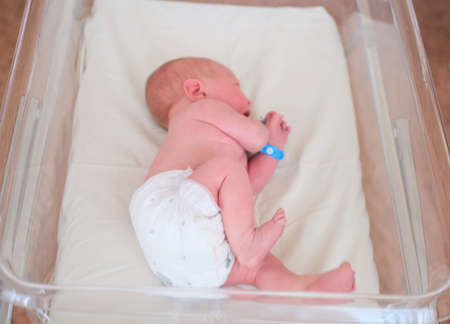 Newborn baby - a boy or a girl in a maternity hospital sleeps in a crib, concept - health care and medicine.の写真素材