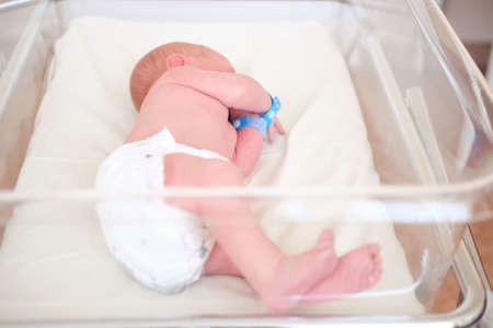 Newborn baby - a boy or a girl in a maternity hospital sleeps in a crib, concept - health care and medicine.の写真素材