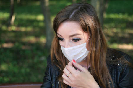 Young girl in protection mask sitting on bench in time pandemic COVID-19. Concept coronavirus, air pollution, restの写真素材