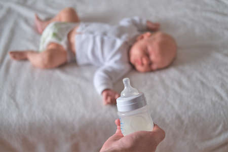 A bottle of milk on the background of a sleeping baby. Concept - breastfeeding.の写真素材