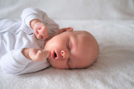 Portrait of a newborn baby with seborrhea sleeping on a white blanket.の写真素材