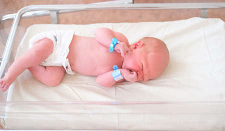 Newborn baby - a boy or a girl in a maternity hospital sleeps in a crib, concept - health care and...