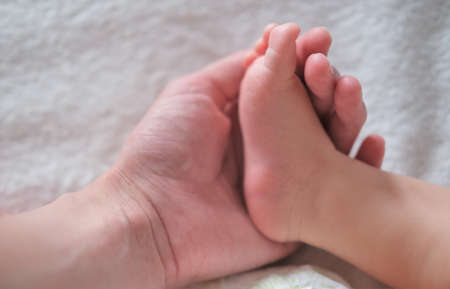 Mom holds the leg of her newborn baby
