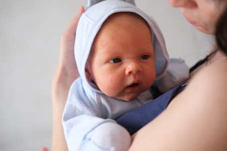 Mom holds her newborn baby in her arms. Portrait of a boy or girl close-up.