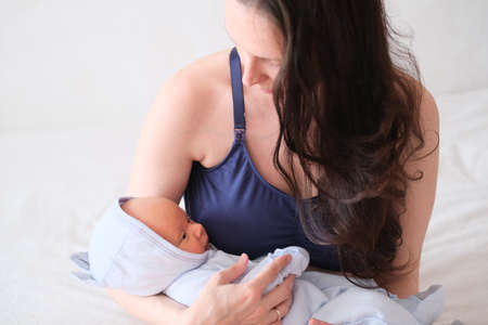 Mom holds her newborn baby in her arms. Portrait of a boy or girl close-up.の写真素材