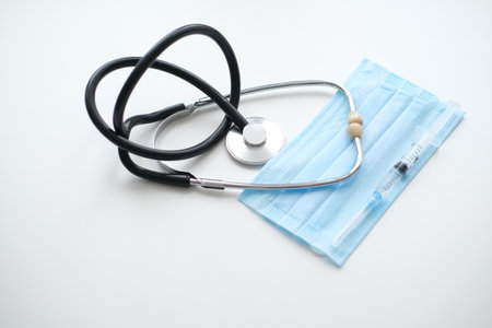 A stethoscope, a medical mask and a syringe for injection lies on a white background, close-up. Concept medicineの写真素材