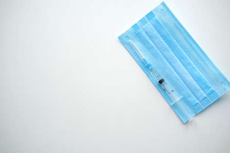 Medical mask and syringe for injection lies on a white background, close-up. Concept medicine.