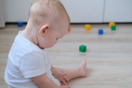 A small child plays on the floor with colored cubes and builds a pyramid out of them.の写真素材