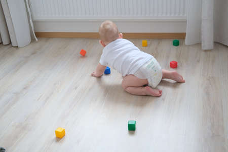 A small child plays on the floor with colored cubes and builds a pyramid out of them.の写真素材