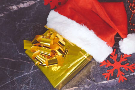 New Year and Christmas gifts. Selective focus. Santa claus hat, boxes with gifts, beads, Christmas toys on a dark background.の写真素材