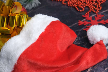 New Year and Christmas gifts. Selective focus. Santa claus hat, boxes with gifts, beads, Christmas toys on a dark background.の写真素材