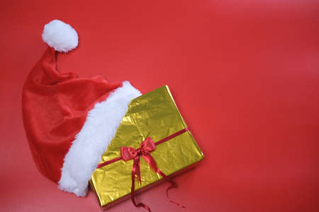 Christmas shopping. List of purchases and gifts for the new year. Santa claus hat lies on a gold box on a red backgroundの写真素材