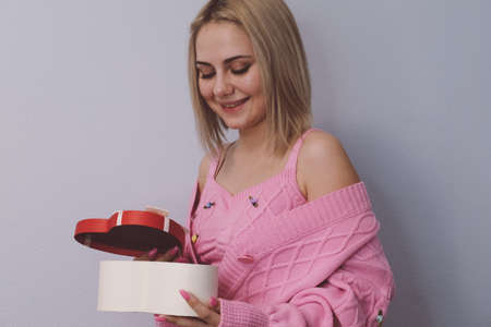 Girl holding a gift in a box in the shape of a heart.Light background, selective focus.Concept black friday, holiday, birthday, womens dayの写真素材