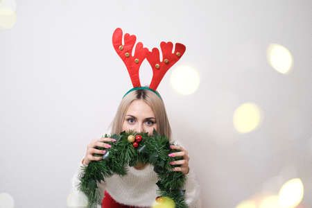 Portrait of a beautiful girl with deer antlers on a white background with bokeh. Concept-Christmas, New Year.の写真素材