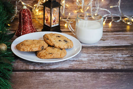 Milk with Christmas cookies for santa claus on a wooden table, selective focus.の写真素材