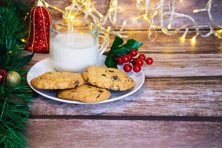 Milk with Christmas cookies for santa claus on a wooden table, selective focus.の写真素材