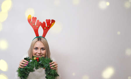 Portrait of a beautiful girl with deer antlers on a white background with bokeh. Concept-Christmas, New Yearの写真素材