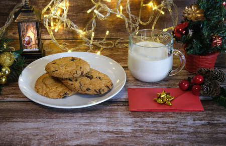 Milk with Christmas cookies for santa claus on a wooden table, selective focus.の写真素材