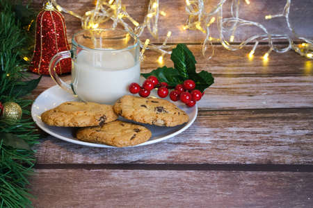 Milk with Christmas cookies for santa claus on a wooden table, selective focus.の写真素材