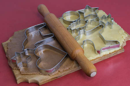 Dough for making homemade gingerbread cookies on a wooden board on a red background.Christmas and New Year 2022 concept. Selective focusの写真素材